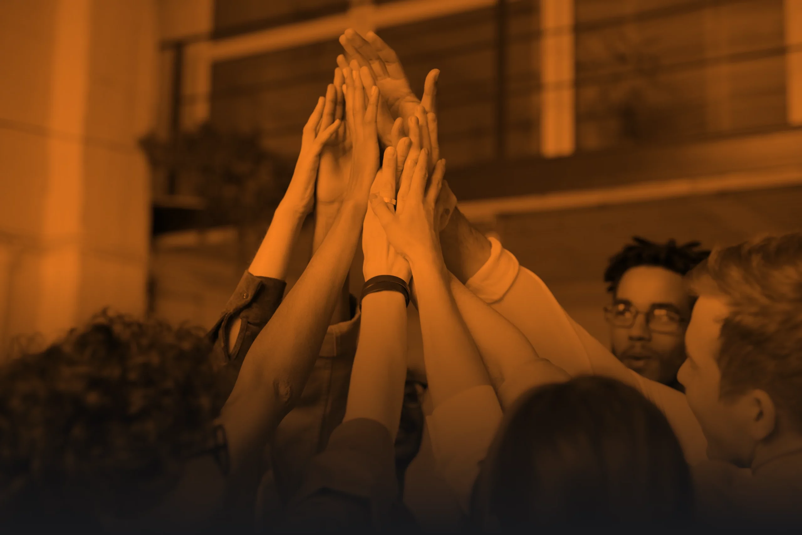 Groupe de personnes levant les mains ensemble en signe de cohésion et d’esprit d’équipe