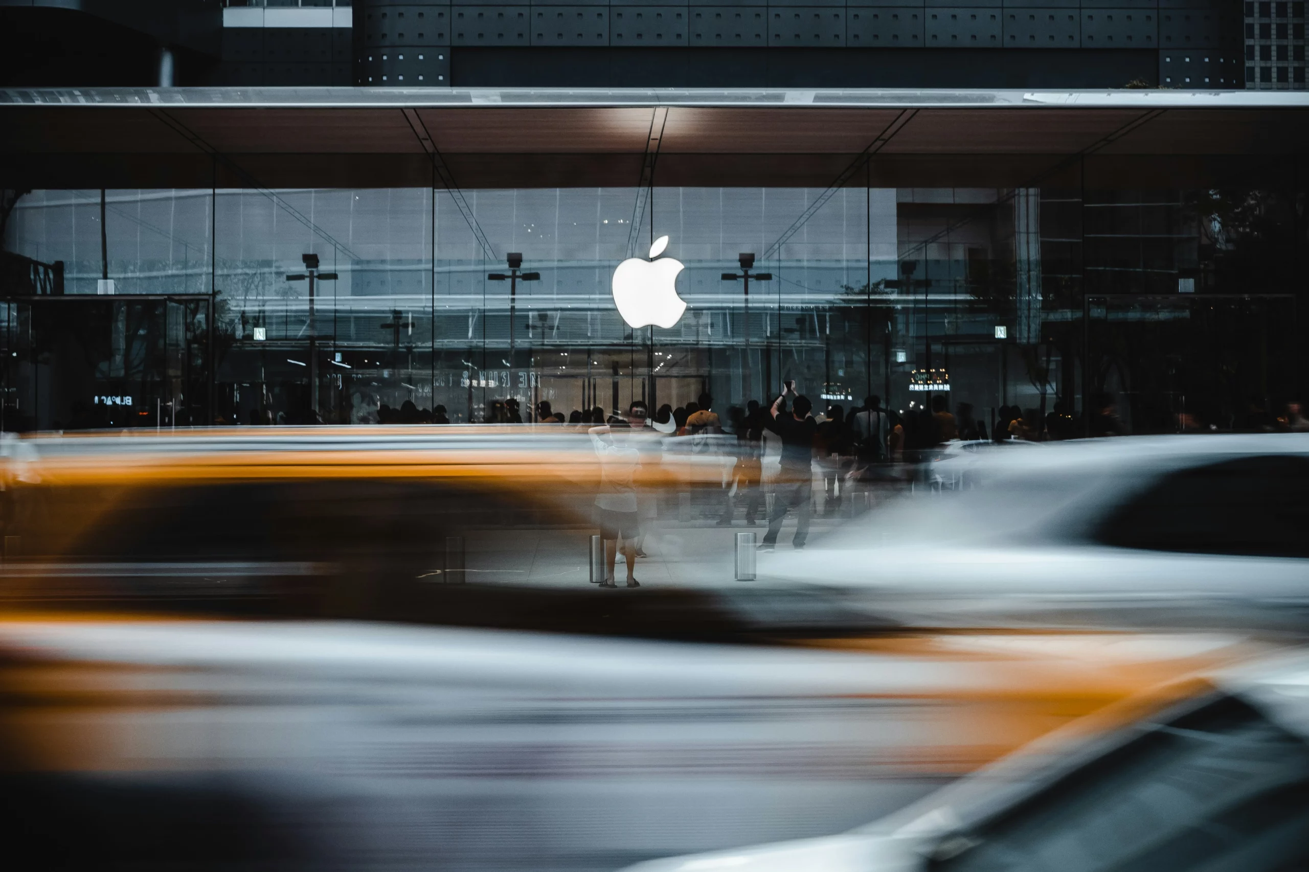 Façade vitrée d’un Apple Store avec le logo Apple, scène urbaine animée en arrière-plan